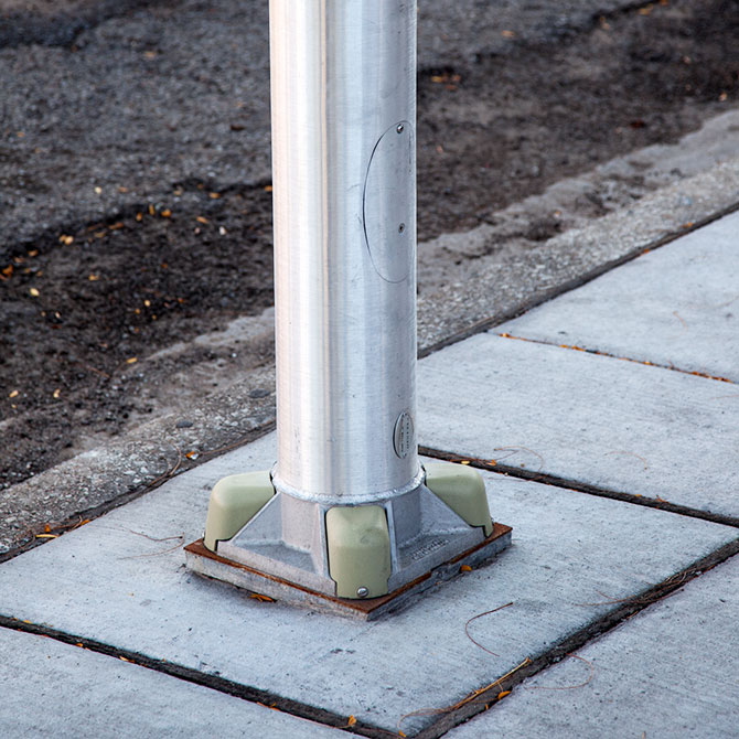 Base of a street light pole anchored into concrete