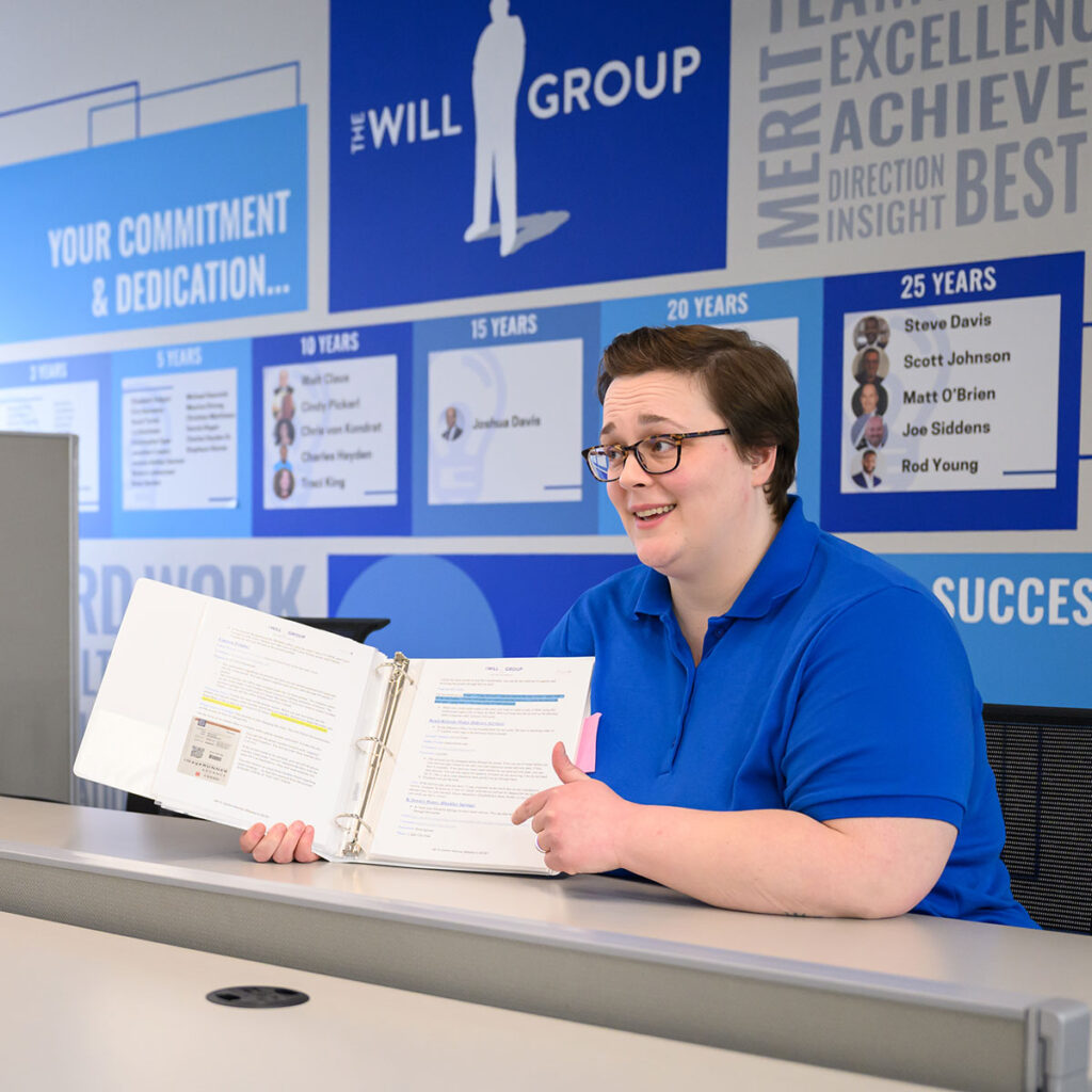 The WIll Group employee sitting at a desk and presenting book materials